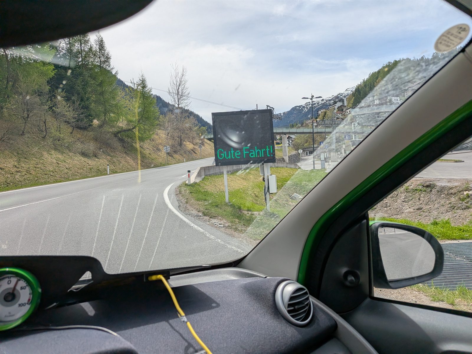 Windscreen view of an Arlberg road with a Gute Fahrt sign