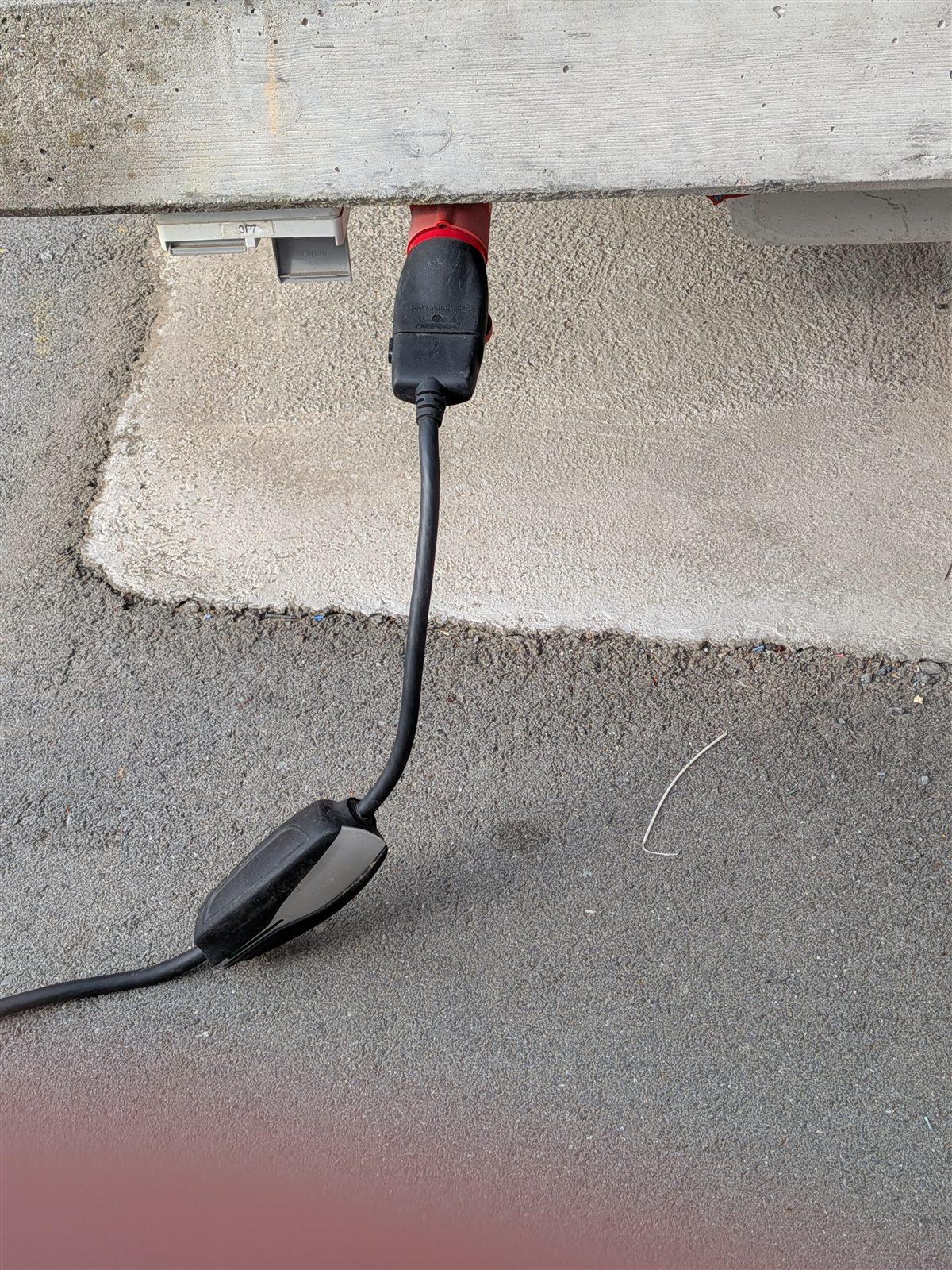 A red CEE-16 three-phase socket with the Tesla Universal Mobile Connector plugged in