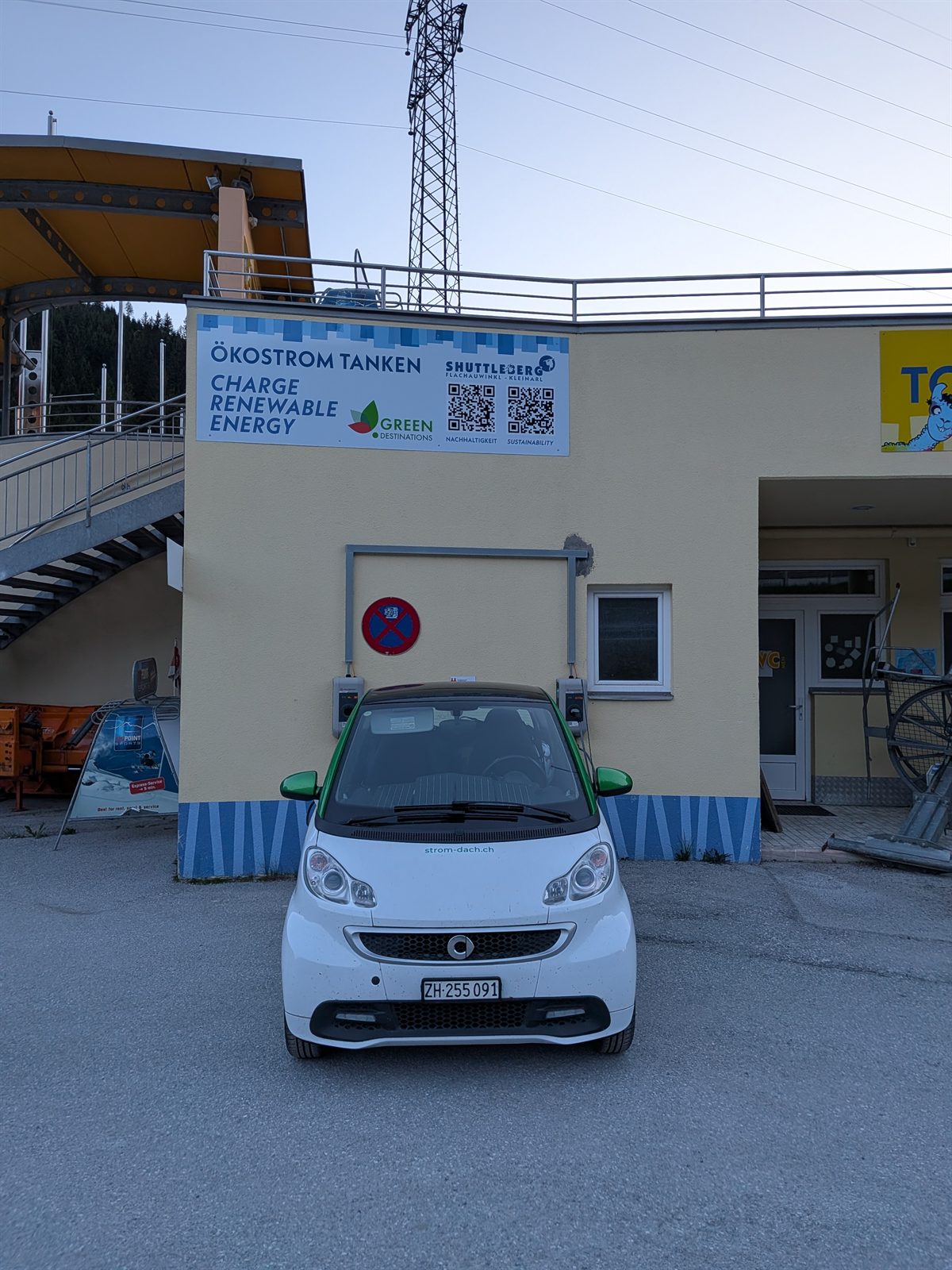 The smart ED parked at a ski-resort charger with a Charge Renewable Energy sign in the Tauern
