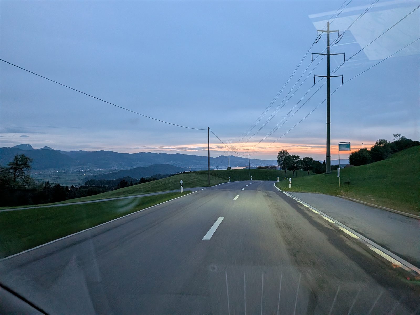 Sunset over a Swiss road descending toward the Obersee with the Alps behind