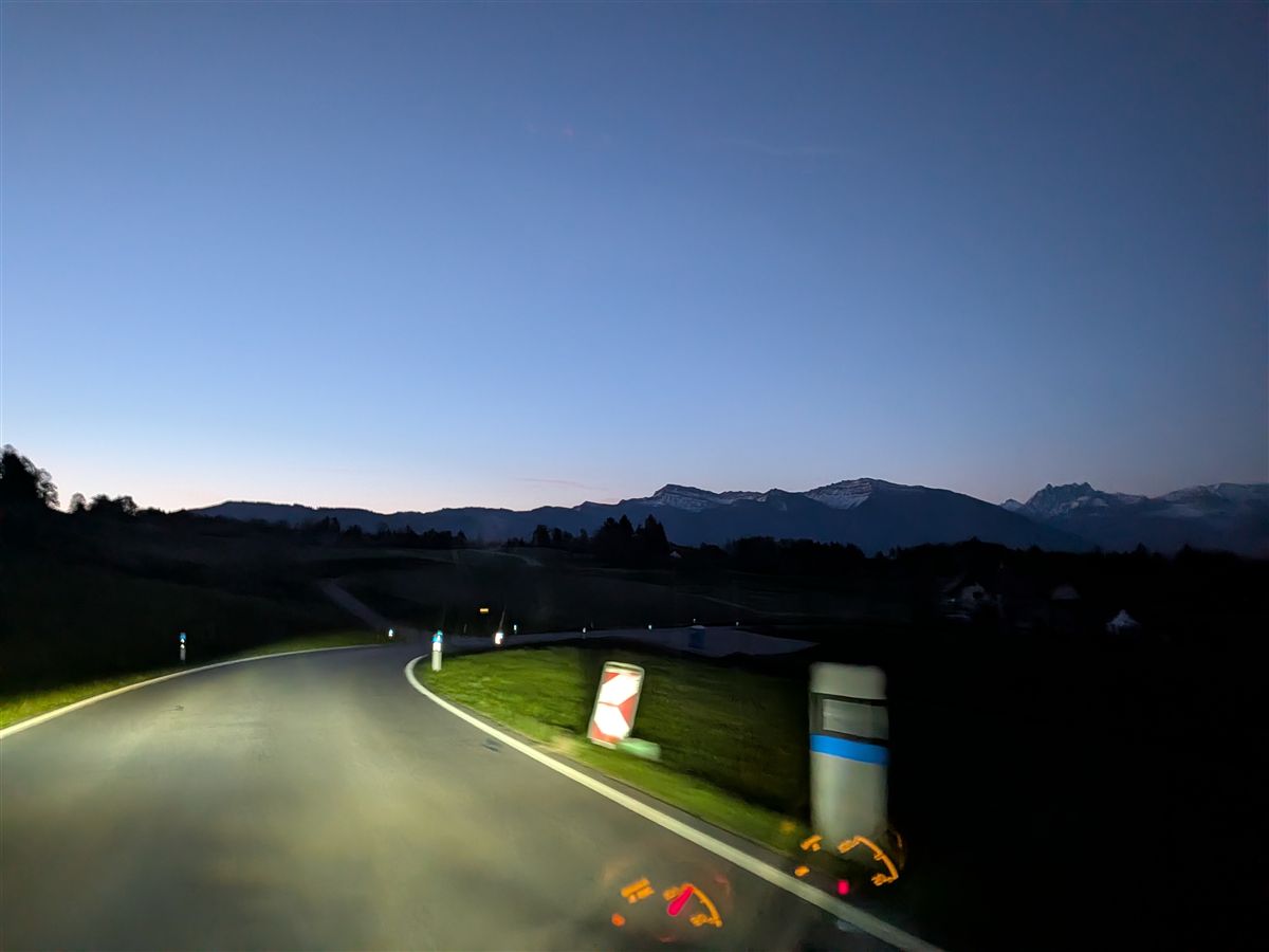 Pre-dawn drive through Swiss countryside, Alps silhouette on the horizon